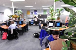 several small circular tables with desktop computers where several students are spread out while studying