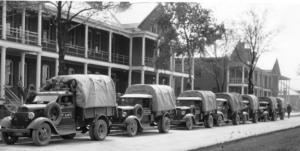 Military trucks parked in front of the twin barracks, circa 1930.