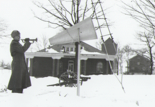 A soldier sounds the trumpet in front of the post guardhouse, circa 1930.