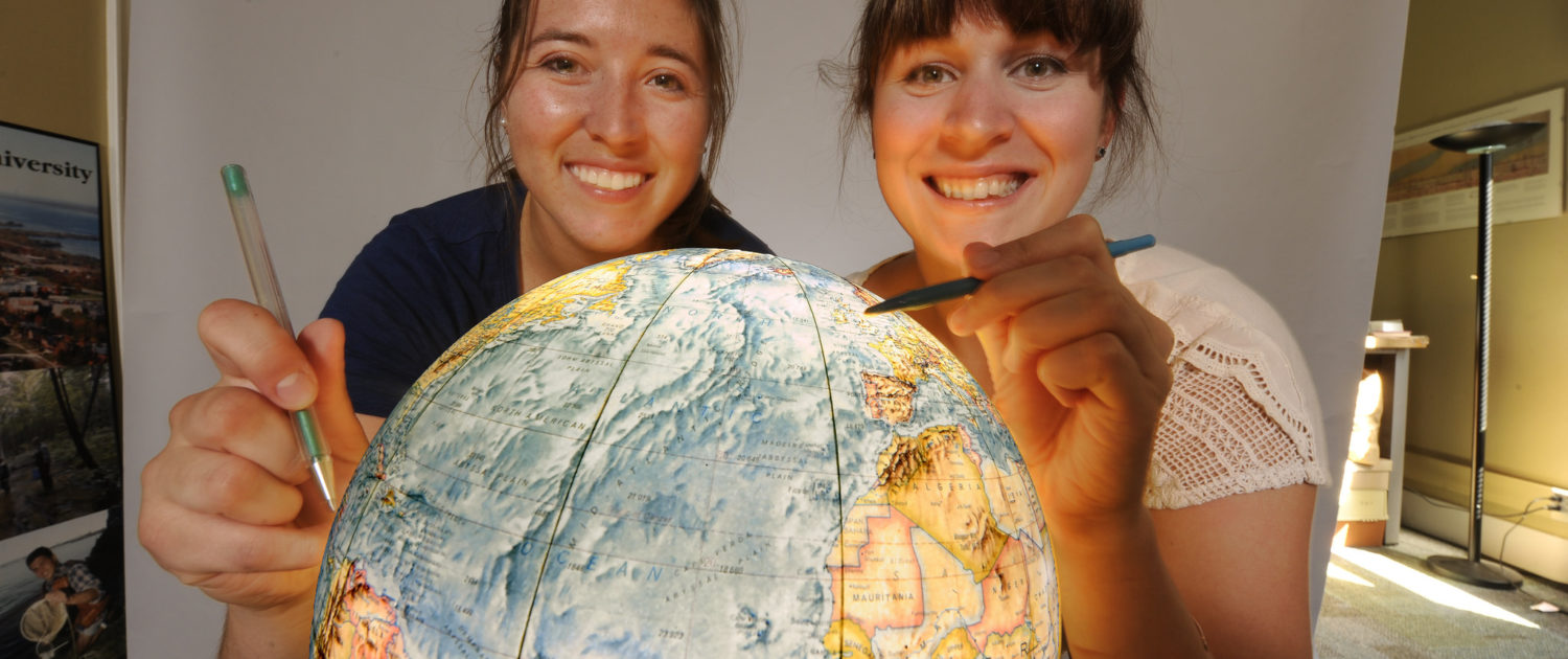 Two students map their future on a globe.