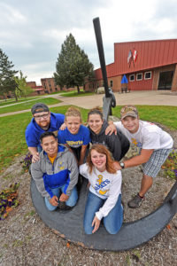 31069791410_786369f8e2_z group of students posing with anchor in front of brick building