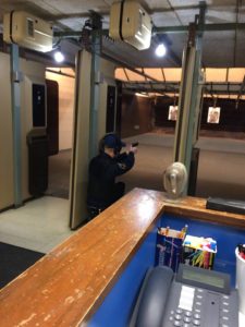 MCOLES Academy cadet in a kneeled shooting postion pointing down range in the indoor shooting range