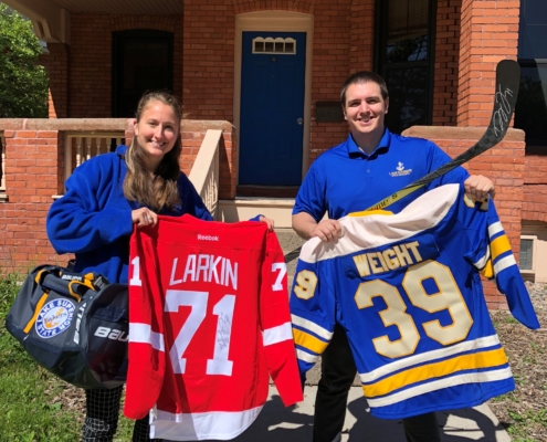 LSSU Foundation staff members pose with items available for auction during the online and live auctions as part of the Lake State Classic.