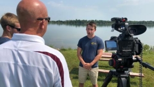 Image of Zachary Johnson in front of a wetland area being interviewed on camera for a documentary