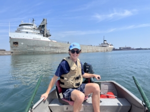 A man on a boat near a freighter.