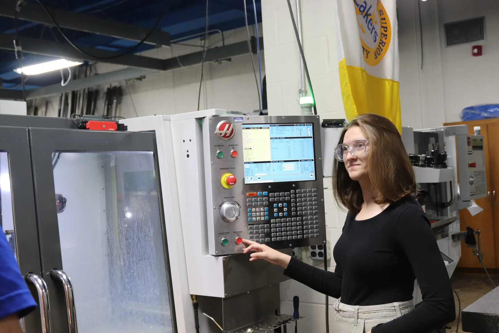 Student standing in front of machinery.