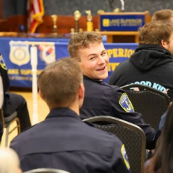 MCOLES graduate turns in his chair, smiling and chatting with a fellow graduate