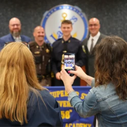Family seen taking photo of graduate and staff with their cell phone