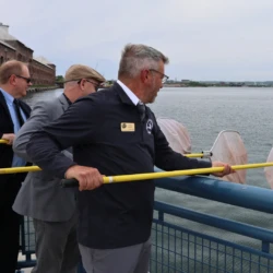 Three organization representatives hold nets over the rail edge just before the ceremonial release.