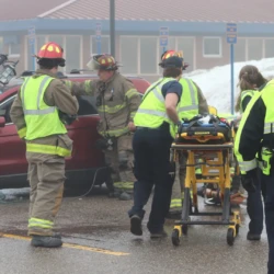 Group of students bring in stretcher to remove patient from car and transport for medical care during simulation.