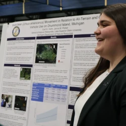 Graduating senior speaking with attendees about research.