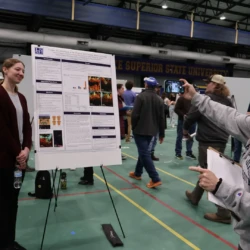 Graduating senior being photographed by supporter next to research board.
