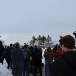 Group of attendees prior to snowman burning with snowman visible in background.