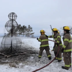LSSU Fire Science students using hose to finish off flames at event.