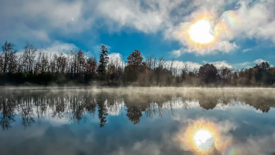 Foggy morning sunrise over a lake with trees on the horizon.